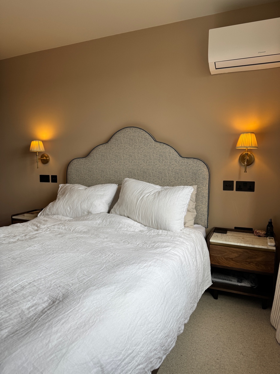 A calm bedroom with brass wall lights and a curved headboard — Wimbledon loft conversion by Jewel Design Studio